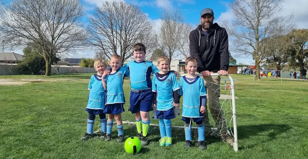 Five junior soccer players with coach, in front of small goal